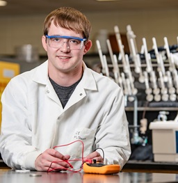 A lab student with goggles smiling.