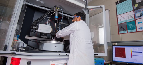 A student in the Chemistry research lab working on a machine.