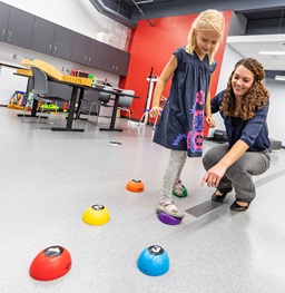 A physical therapist having a child do a physical therapy exercise.