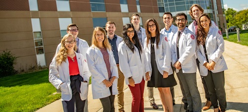 A group of Physician Assistant Students stand outside of the Med School building