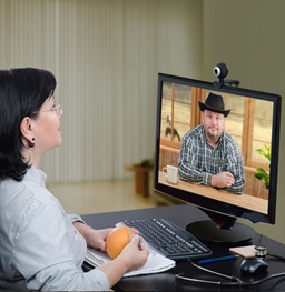 Two people talk over the computer through a webcam.