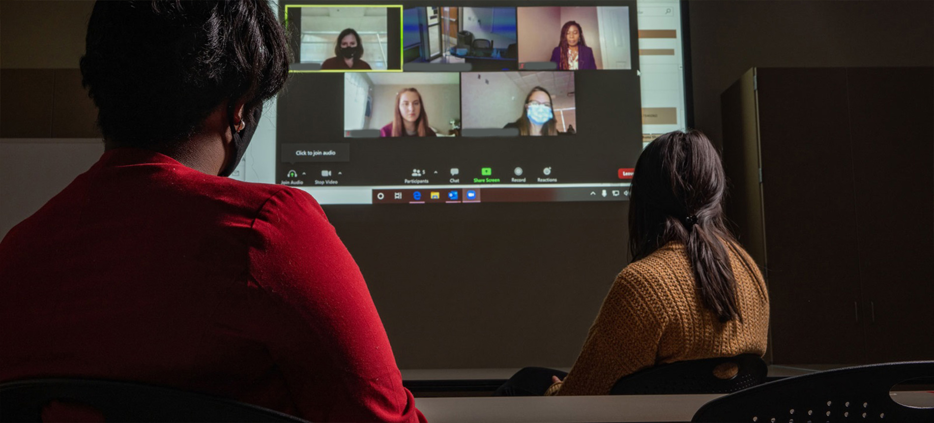 Two students interact with their class through a Zoom meeting.