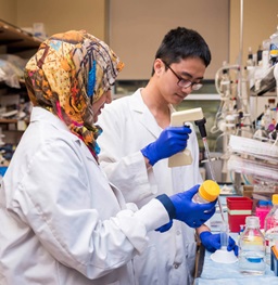 Two BBS students conducting lab research with goggles on.