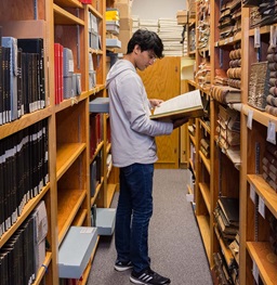 Student in library looking at old book.