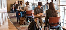 Students Sitting at Tables Talking and Studying.