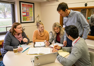 A teacher discussing at a table with students.