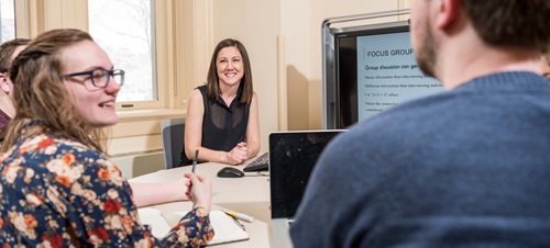 People talking at a table with a computer screen