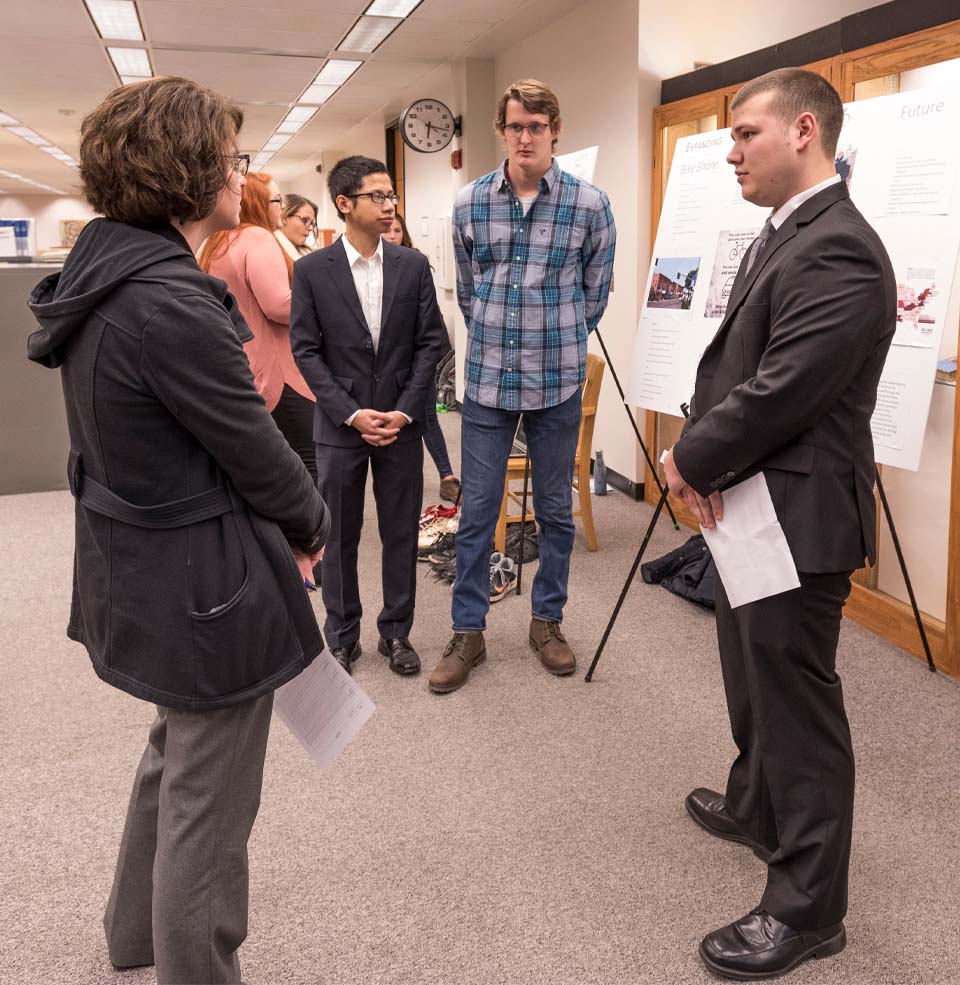 Students presenting research to visitors.
