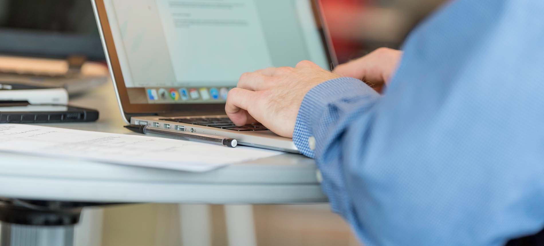 A Student Typing on a Laptop.