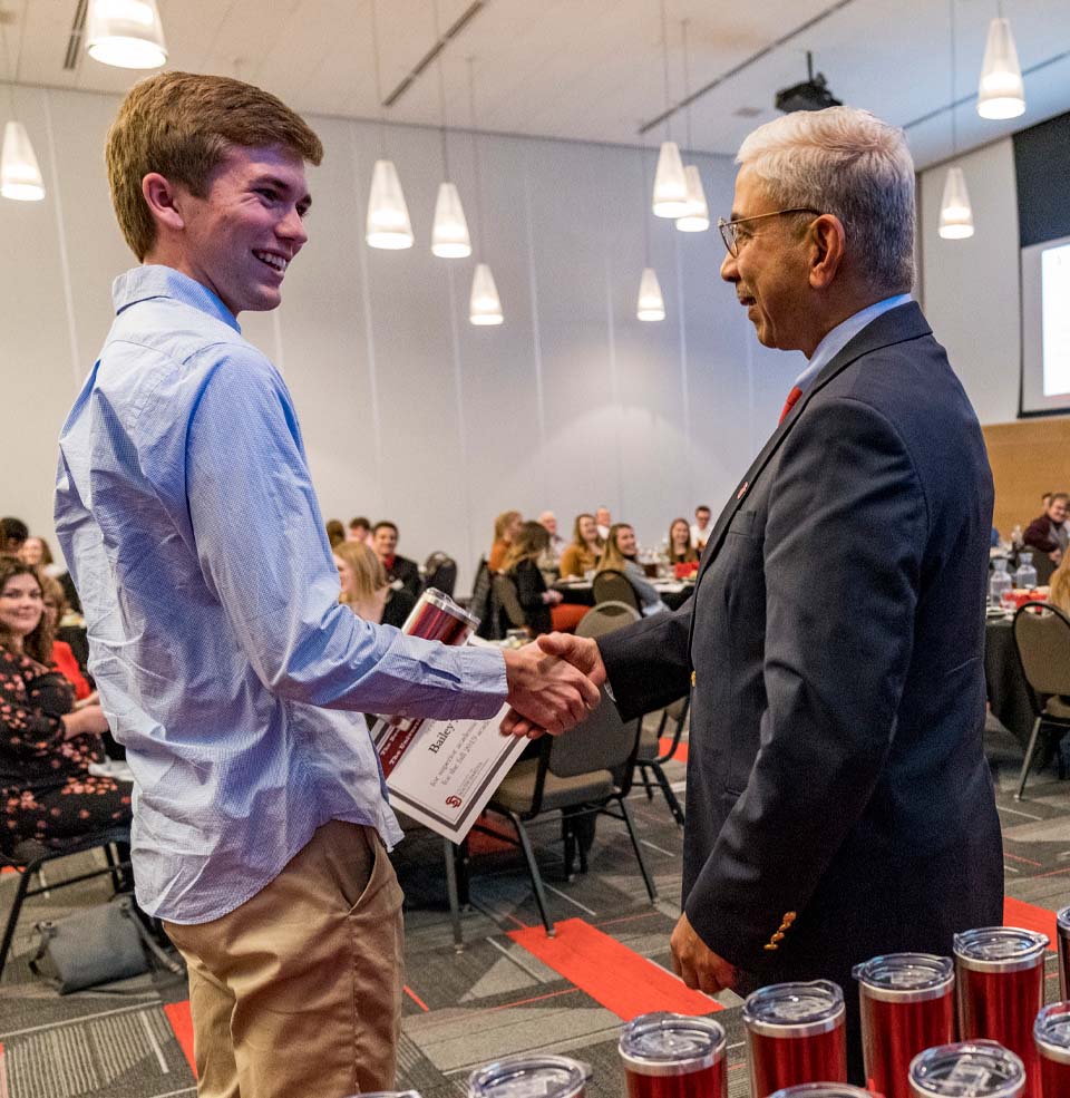 A Beacom student proudly shakes hands with the Dean of the Beacom school of Business 