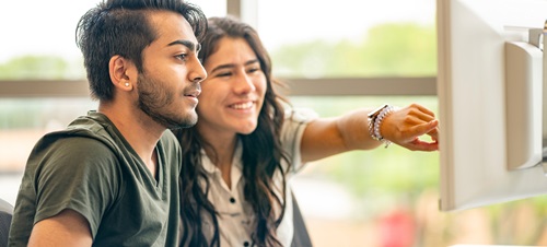 Two students working on a computer together in the Ellis Finance Lab.