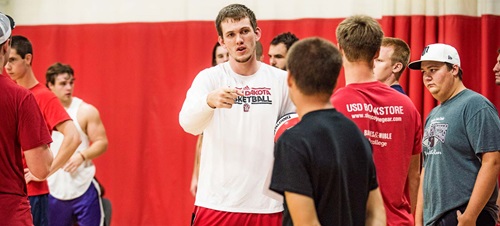 Coach Speaking to a Group of Students in a Gym.