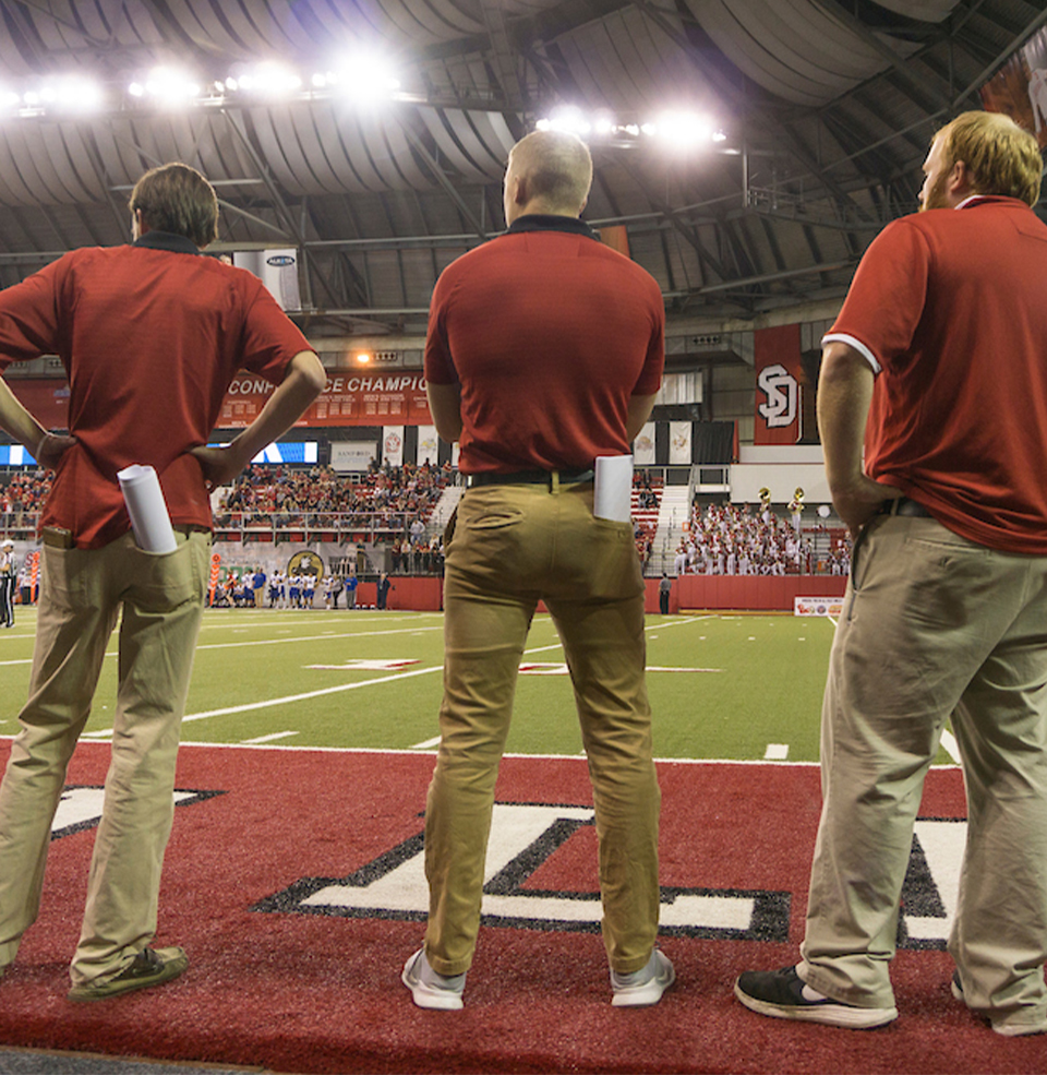 Football interns on the sideline at a game.