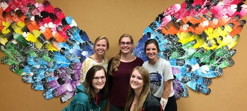 Students pose after creating a collage.