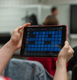 A student holding a music technology tablet.