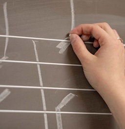 Hands drawing music notes on chalkboard.