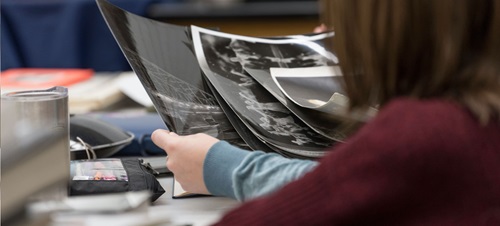 Professor John Banasiak reviews negatives with photography student in photo lab studio