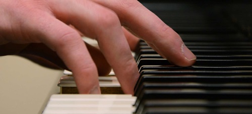 Hands playing a piano.