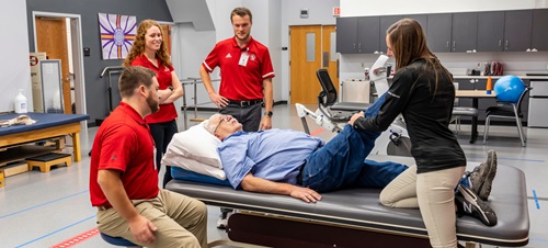 A group of OT students helping an elderly man.