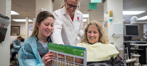 A dental hygiene student showing a chart to a patient.
