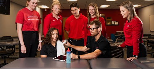 Physical therapy students standing around a test being conducted.