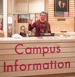A student holding the Yote sign at the MUC campus information desk.
