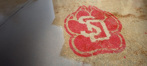 A chalk USD logo drawn on the sidewalk in red.