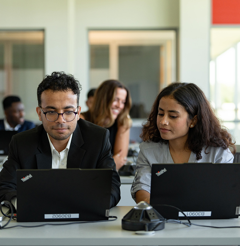 Two students sitting in class looking at a computer.