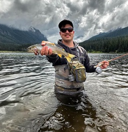 A student standing in the Missouri River holding a fish.