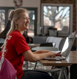 Female Smiling While Sitting at Table with Laptop