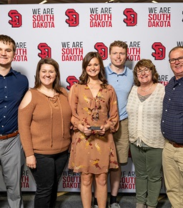 A USD family posing for a photo with an award.