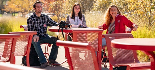 Three students sitting at a table outside of the Muenster University Center