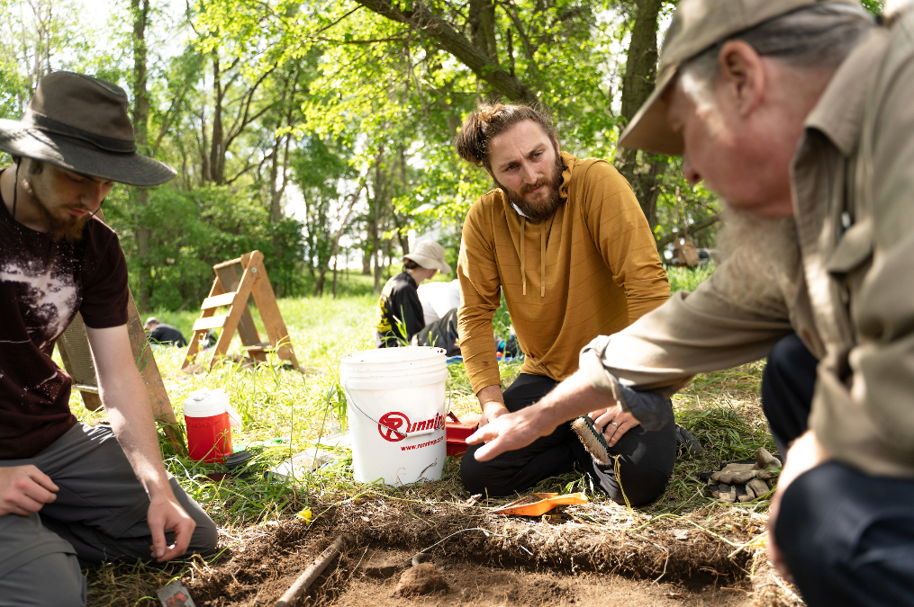 Archeology students and faculty digging in a field.