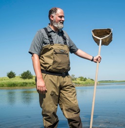 Biology Chair Jake Kerby standing in the Missouri River with a net.