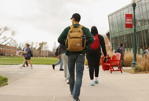 A student walking with his backpack on main campus.