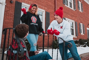 Three students in USD Gear laughing in a group together.