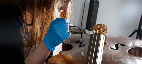 A student working on her string instrument up close.