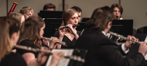 A student playing a flute in their USD orchestra session.