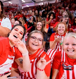 Coyote Crazies holding up the Yote hand symbol at a volleyball game.