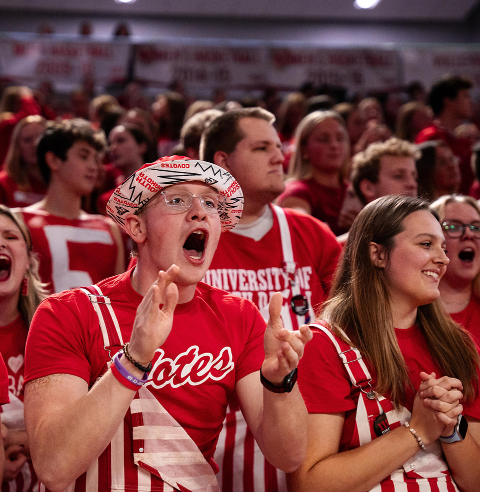 Coyote Crazies cheering in the striped overalls at a volleyball game