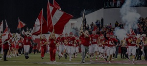 Football players charging the field carrying flags in the DakotaDome.