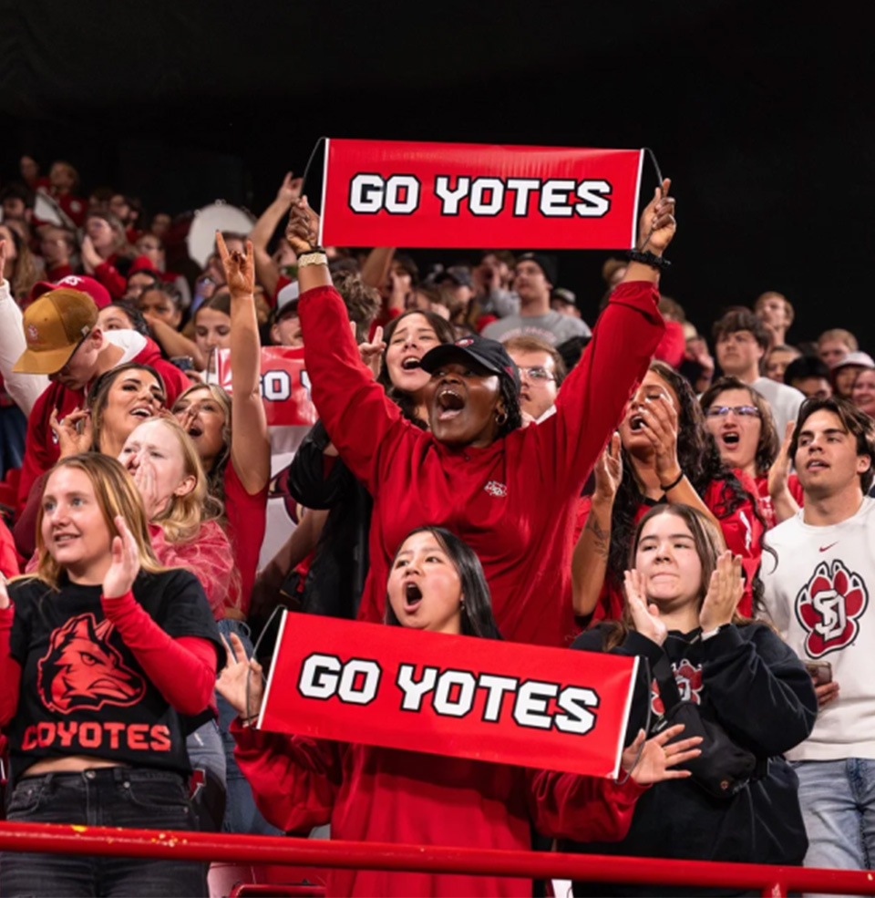 Large crowd with Go Yotes signs at USD Athletic event in the Dakota Dome