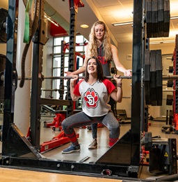 Two girls lifting in the Wellness Center.