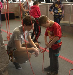 A Climbing wall worker helping a child hook up his equipment to the wall.