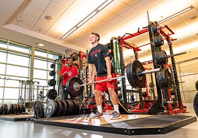 A USD student deadlifting weights while another cheers them on.