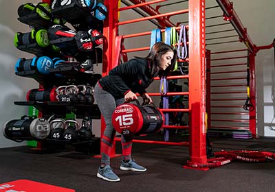 A USD student rowing a weighted bag in the functional training room.