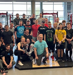 Lifters posing for a photo in front of weights at the liftaton