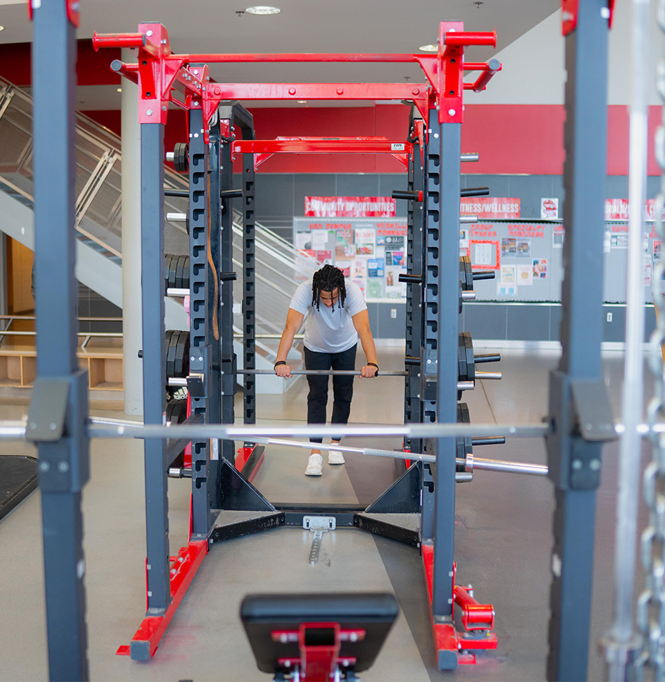 person lifting weights on a squat rack in the wellness center