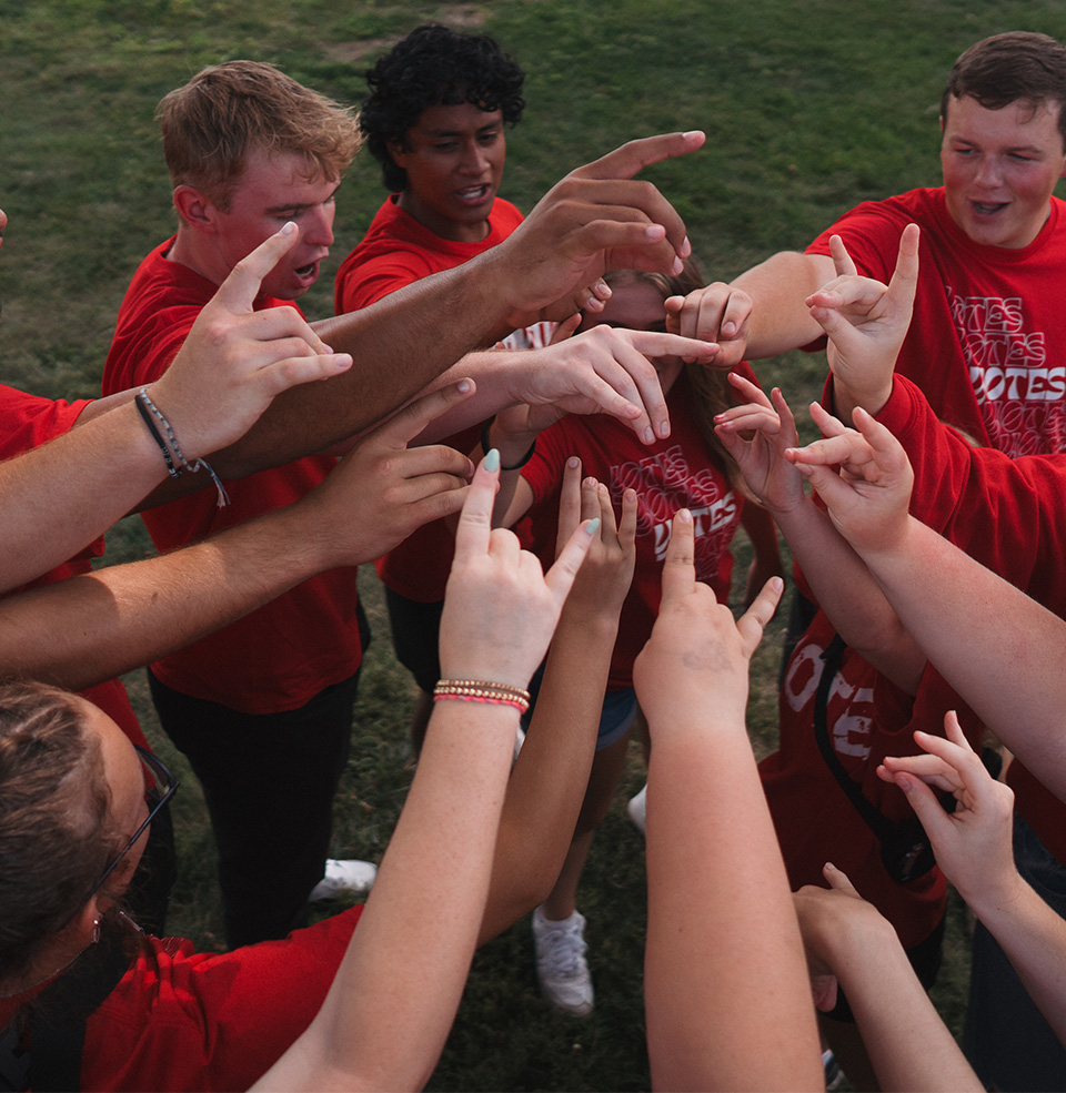 Group of students putting up yote hands to break down a huddle