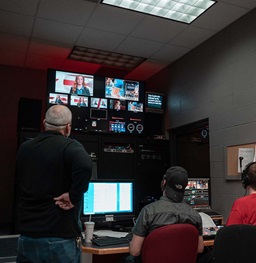 Two students and an advisor running the production boards of Coyote News